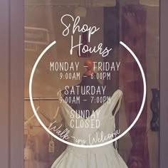 a white dress is on display in a shop window with the words shop hours written across it