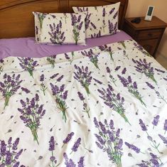 a bed with lavender flowers on it and two pillows