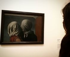 a woman looking at a painting with two women wearing headscarves on it's head