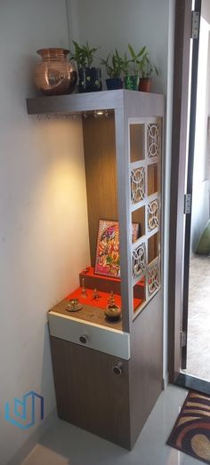 a room with a small cabinet in the corner and some plants on top of it