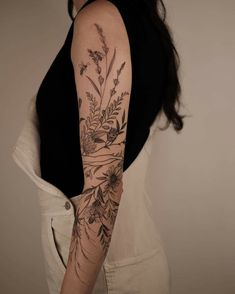 a woman's arm with flowers and leaves tattooed on the back of her arm