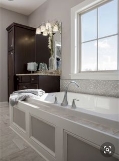 a large bath tub sitting under a bathroom mirror