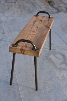 a wooden bench sitting on top of a cement floor next to a black handlebar