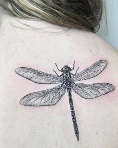 a black and white photo of a dragonfly on the back of a woman's shoulder