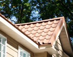 a house with a brown roof and trees in the background