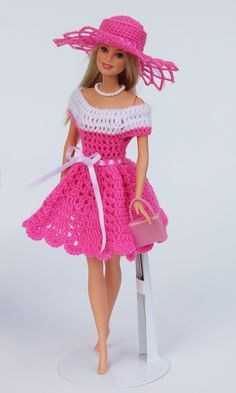 a barbie doll wearing a pink crocheted dress and matching hat with a purse