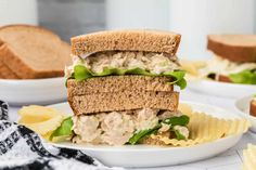 a close up of a sandwich on a plate with chips in the foreground and another sandwich in the background