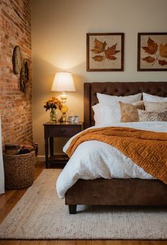 a bedroom with a bed, nightstand and lamp in front of a brick fire place