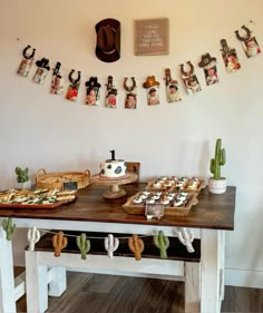 a table topped with pictures and desserts next to a wall mounted cowboy hat on the wall