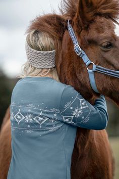 a woman is hugging a horse with her face close to it's neck and wearing a headband