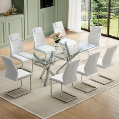 a glass dining table with white chairs and a vase on the floor in front of it