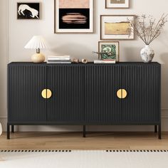 a black sideboard with gold handles in front of pictures on the wall and floor