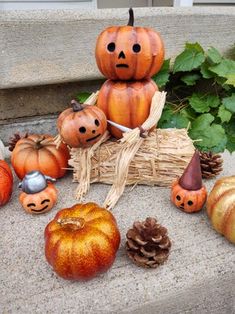 pumpkins and pine cones are arranged on the front steps with faces carved into them