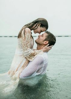 a man holding a woman in the water while she holds her up to her chest