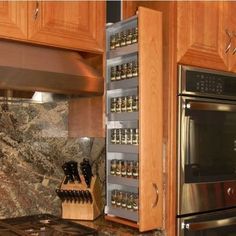 a kitchen with granite counter tops and stainless steel stove top oven, spice rack on the wall