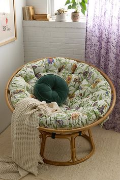 a chair with a green cushion on it in front of a window next to a blanket