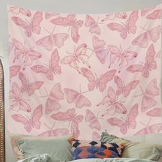 a pink wall hanging over a bed covered in pillows