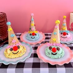 four decorated birthday cakes sitting on top of plates with clown hats and decorations around them