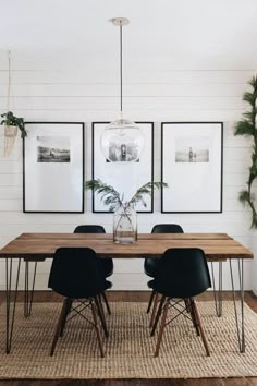 a dining room table with black chairs and framed pictures on the wall above it,