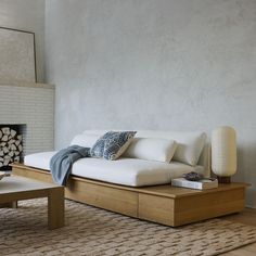 a white couch sitting on top of a wooden table next to a fire place in a living room