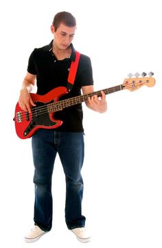 a man holding a red bass guitar in his right hand and looking down at it