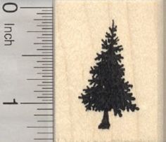 a rubber stamp with a pine tree on it and measuring tape in front of it