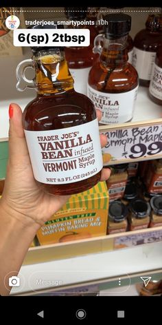 a person holding up a jar of honey in front of shelves with other products on it