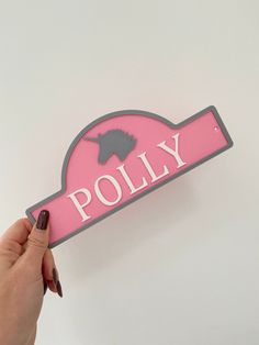 a person holding up a pink sign with a horse on it that says polly