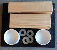 three white bowls sitting on top of a table next to wooden planks and measuring tape