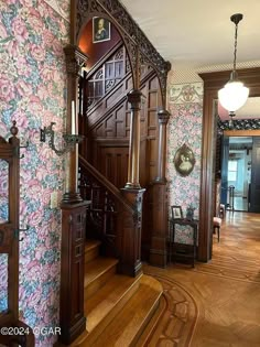 an ornate wooden staircase with floral wallpaper