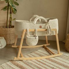 a white wicker baby's cradle sitting on top of a rug next to a potted plant