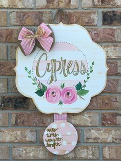 a sign on the side of a brick wall that says cypress with pink flowers and green leaves