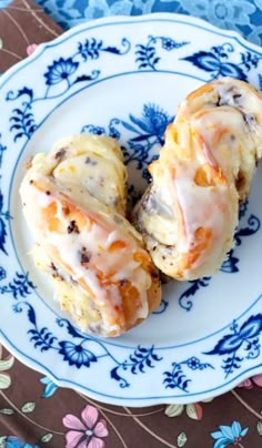 two glazed donuts sitting on top of a blue and white plate