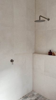 a white tiled bathroom with a shower head