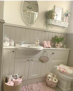 a white bathroom with pink rugs and accessories on the floor in front of a mirror