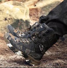 a pair of black hiking shoes sitting on top of a dirt ground next to rocks