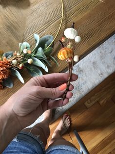 a person is holding some kind of flower in their hand on the floor next to a table