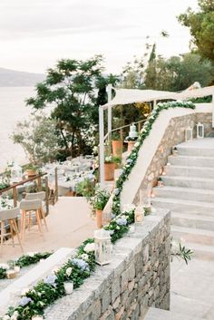 an outdoor wedding setup with flowers and greenery on the steps leading up to the water