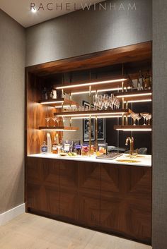 a bar with lots of wine glasses on it's shelves and lights above the counter