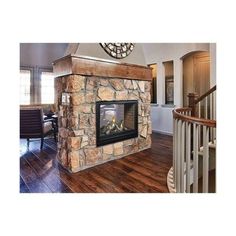 a living room with a stone fireplace and wooden floors in front of a clock on the wall