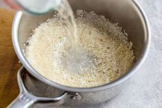 rice being cooked in a pot with water pouring from the top and on to the bottom