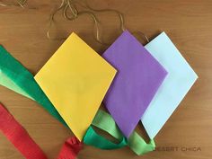 four different colored pieces of paper tied together on a wooden table next to a string