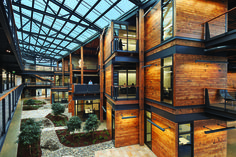 two pictures of the inside and outside of a building with wooden walls, glass roofing and