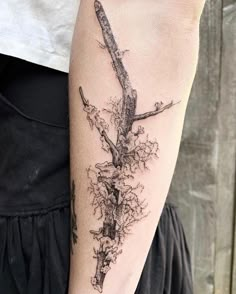 a woman's arm with a branch tattoo on the left side of her arm