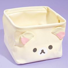 a small white box with a bear face on the front and sides, sitting on a purple surface