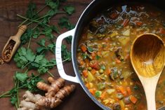 a wooden spoon in a pot filled with vegetable soup and garnished with parsley