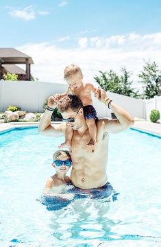 a man holding a young boy while standing in a swimming pool