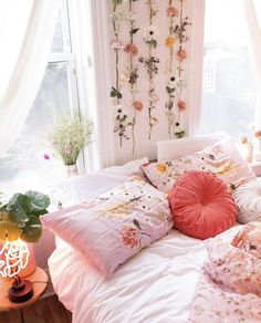 a bed with pillows and flowers on the wall next to a window in a bedroom