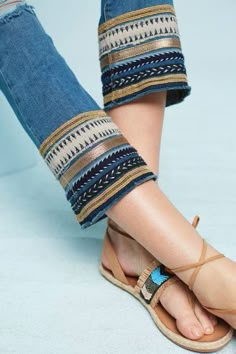 a woman's feet in sandals and jeans on a blue surface with her legs crossed