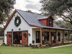 a white barn with red doors and wreaths on the windows